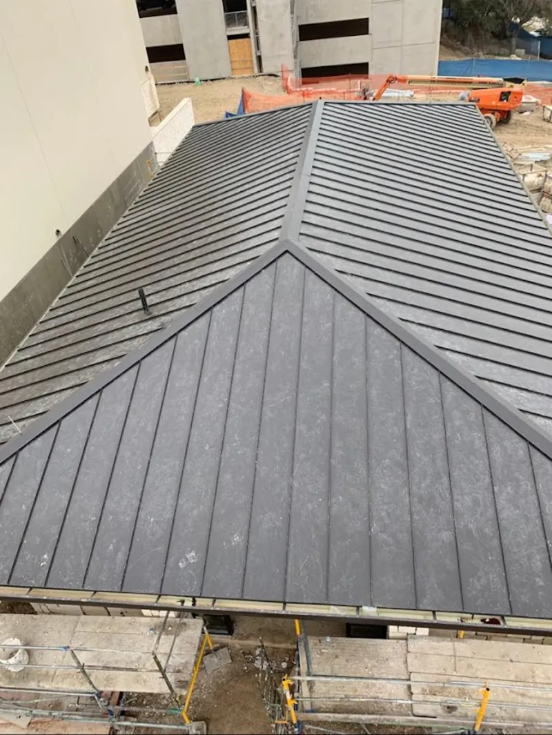 Commercial metal roof construction with crane equipment in Sterling